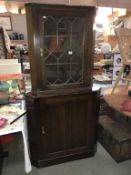 A dark oak corner cupboard with leaded glass cabinet door