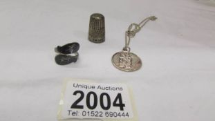 A silver St. Christopher on chain, a silver ring and a silver thimble.