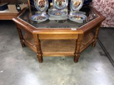 A large dark wood stained octagonal coffee table with bevel glass top & bergere cane under shelf