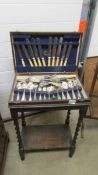 A canteen of cutlery in an oak barley twist leg stand.