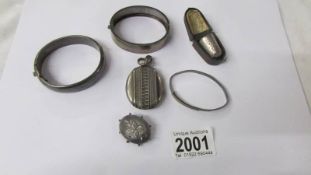 Three silver bangles, a silver locket, a silver brooch and a silver thimble. 60 grams.