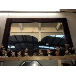 A large dark wood stained bevel edged mirror