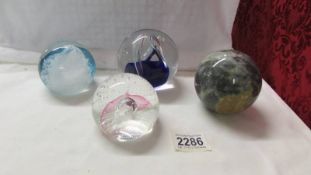 Three glass paperweights and a marble ball.