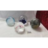 Three glass paperweights and a marble ball.