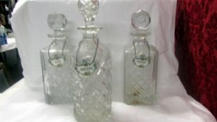 A pair of cut glass decanters and one other, all with labels.