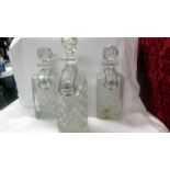 A pair of cut glass decanters and one other, all with labels.