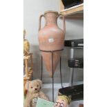 A large terracotta vase on a metal stand.