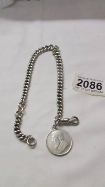 An antique silver kerb link chain with silver shilling dated 1895. 55.1 grams.