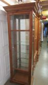 A tall pine display cabinet with bevelled glass panels.