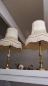 A pair of brass table lamps with fringed shades.