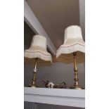 A pair of brass table lamps with fringed shades.