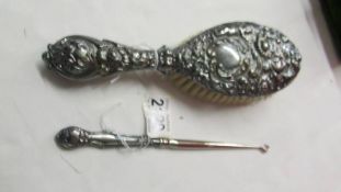 A silver backed hair brush and a silver handled button hook.