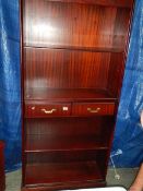 A mahogany effect book case with 2 drawers.