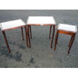 A nest of 3 tables with leather insets and glass tops.