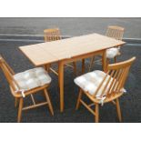 A solid pine extending dining table and 4 Ercol style chairs.