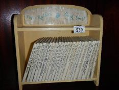 23 Beatrix potter books on a painted book shelf.