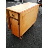 A good oak drop leaf table with end cupboard and drawer.