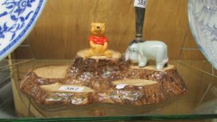 A Beswick Winnie the Pooh and Eeyore on a Beswick stand.