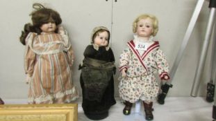 Two old porcelain dolls and another with a bottle as its body.