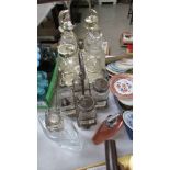 Two four bottle condiment sets on plated stands and two scent bottles.