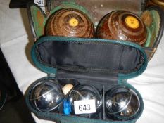 A cased pair of lawn bowls and a boules set.