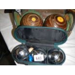 A cased pair of lawn bowls and a boules set.