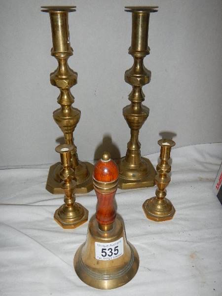 Two pairs of brass candlesticks and a brass bell.