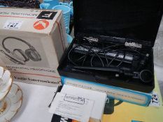 A boxed vintage microphone and a boxed pair of head phones.