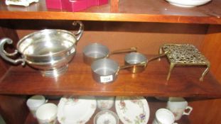 A large silver plate dish, a brass trivet and a set of three copper pans.