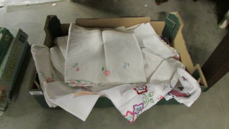 A box of linen including embroidered table cloths.