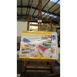 An artist's easel and a set of watercolour paints.