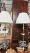 A pair of chrome and glass bedside lamps with shades.