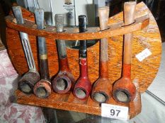 A quantity of old pipes on an oak pipe rack