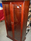 A dark wood stained 2 door bookcase/display cabinet with deep cut glazed doors