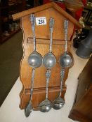 A set of 6 ladles/spoons with figural handles on an oak rack