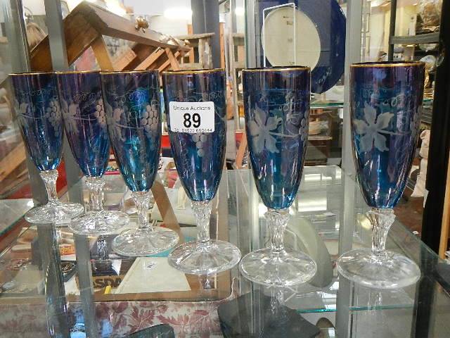 A set of 6 blue cut glass flutes/glasses