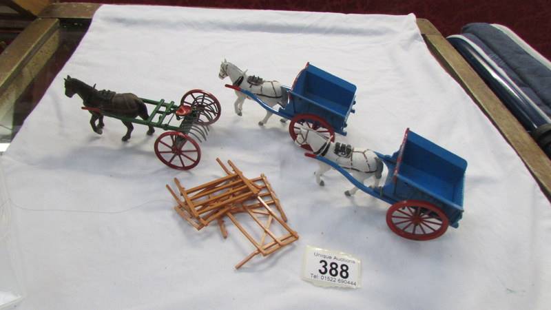 Two Britain's farm carts and a hay rake all with plastic horses.