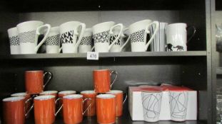 Two shelves of new mugs including designer.