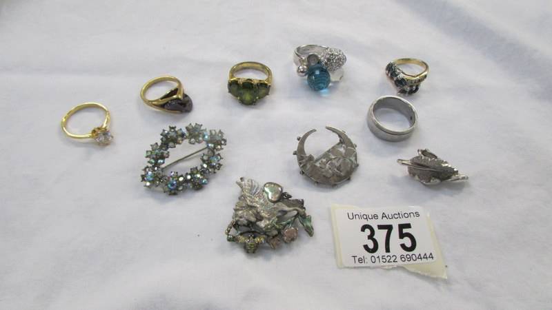 Six assorted dress rings and three brooches.