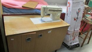 A sewing machine in cabinet. (Collect only)