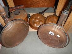 Two copper warming pans, two copper moulds and a copper kettle.