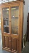 A pine cabinet with glazed doors. (Collect only)