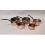 Set of five copper and metal saucepans.
