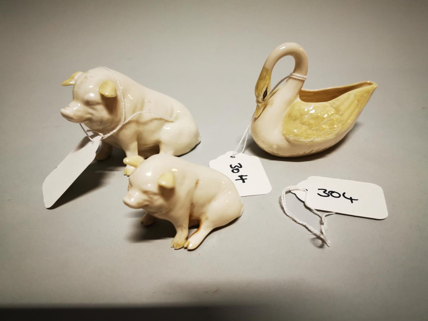 Two modern Belleek models of pigs and a swan.