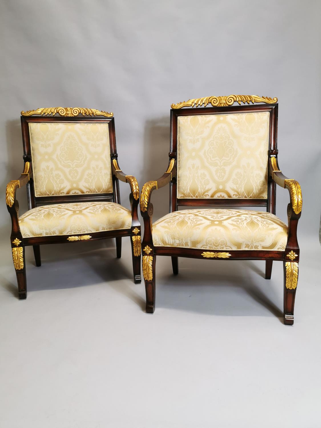 Pair of upholstered gilded mahogany open armchairs