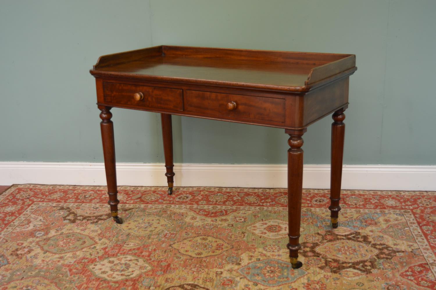 Victorian mahogany two drawer writing table on four turned legs.