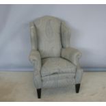 Generously proportioned winged back armchair with quality upholstery, standing on tapered legs 90