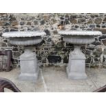 Pair of polystone urns on pedestals.