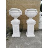 Pair of moulded stone Urns on pedestals.