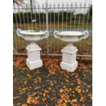 Pair of heavy cast iron urns on plinths.